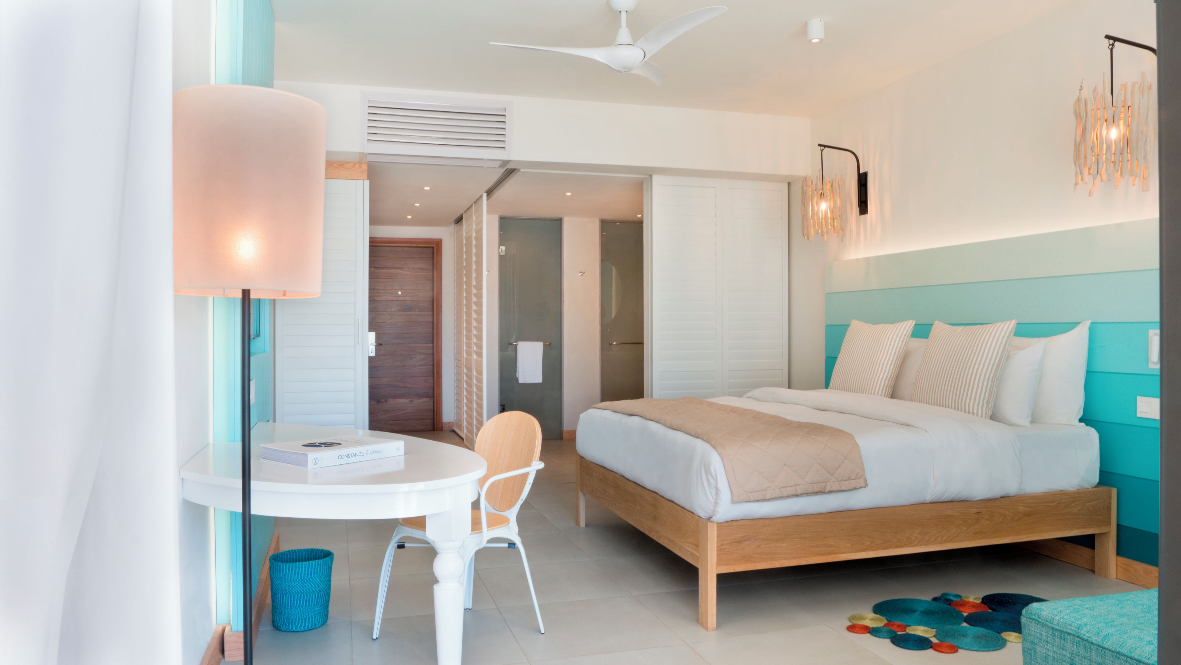 Una habitación de hotel moderna con una cama, un escritorio, una silla y un ventilador de techo.