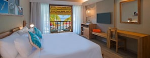 Habitación de hotel con cama, escritorio, silla, televisión y balcón con vista a la piscina.