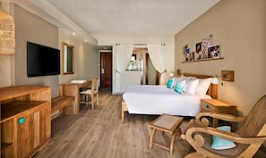 A hotel room with a bed, wooden furniture, a TV, and artwork on the wall.