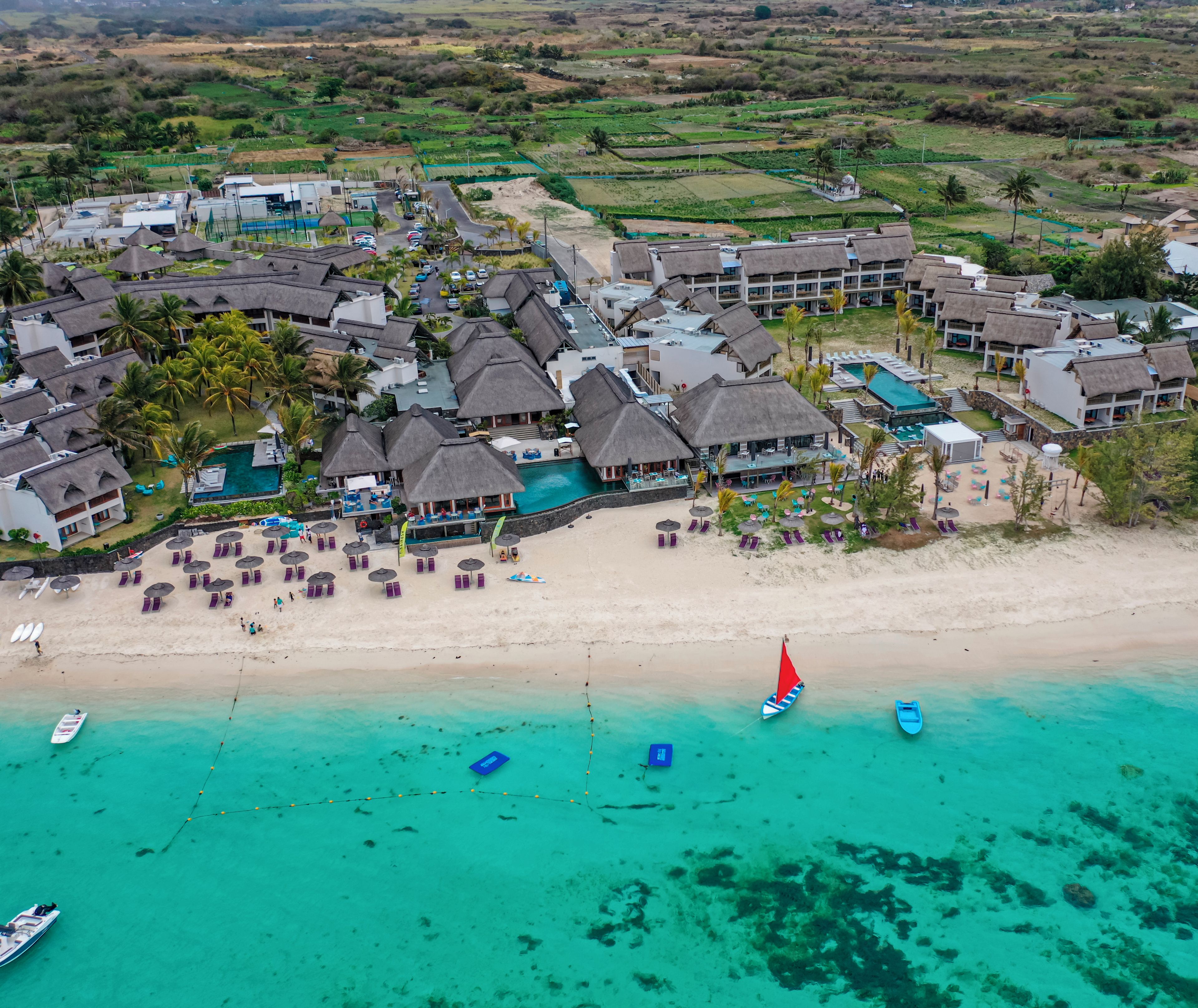 Un resort con varias cabañas sobre el agua, una playa y una piscina.