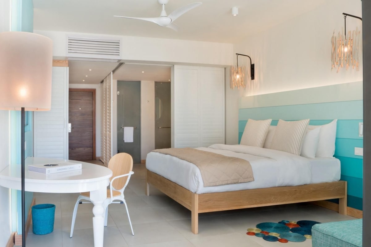 Una habitación de hotel moderna con cama, escritorio, silla y ventilador de techo.