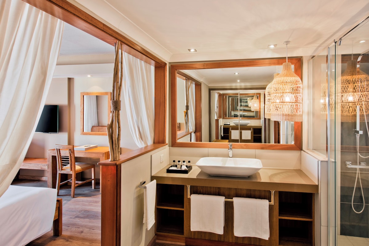 Un baño moderno con un espejo grande, tocador de madera y cabina de ducha de vidrio.