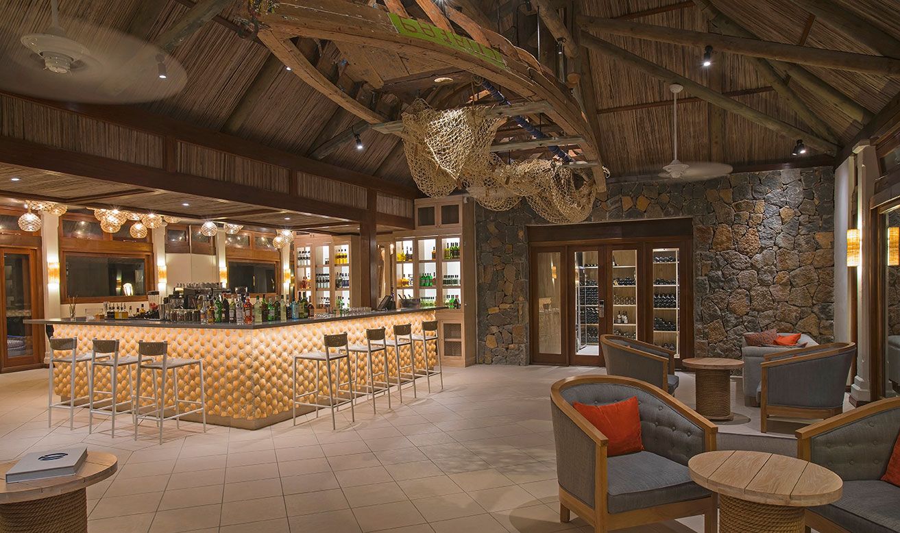 A bar area with stools, a counter, and a stone wall.
