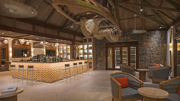 A bar area with stools, a counter, and a stone wall.