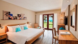 Camera d'albergo con un letto grande, una scrivania con sedia, una televisione e vista sull'oceano dalla finestra.