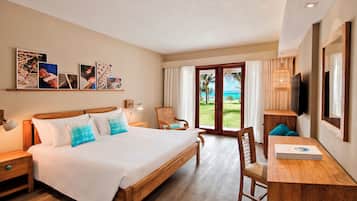 Habitación de hotel con una cama grande, un escritorio con silla, televisión y vista al océano a través de la ventana.