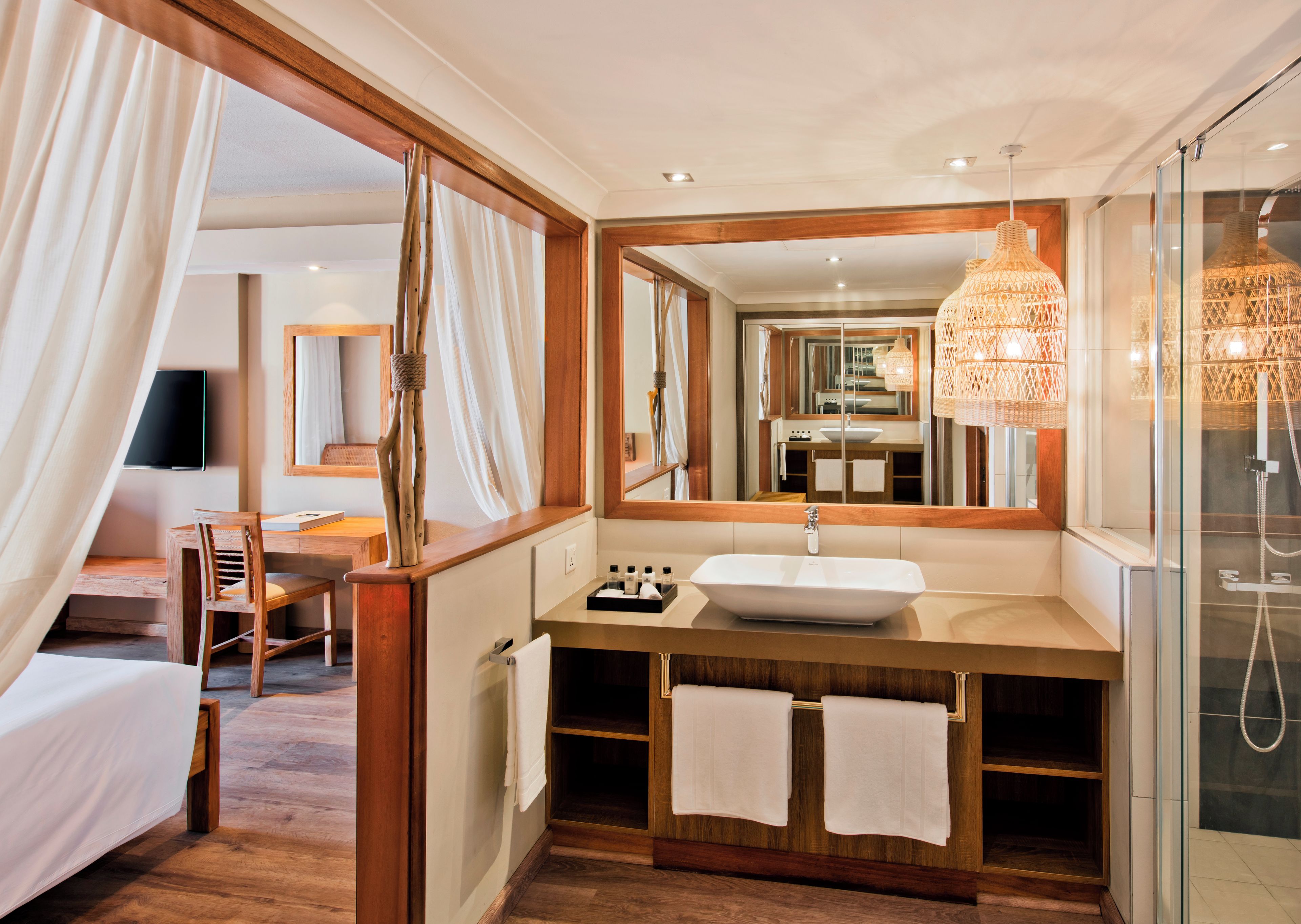 Un baño moderno con un espejo grande, tocador de madera y cabina de ducha de vidrio.