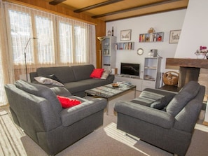 Ein Wohnzimmer mit einer Sofagarnitur, einem Couchtisch, einem Fernseher und einem Kamin.