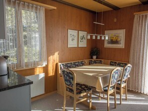 Zona pranzo con tavolo e sedie, stampe botaniche incorniciate alle pareti e una pianta in vaso.