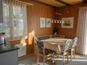Ein Essbereich mit Tisch und Stühlen, botanische Drucke als Wanddekoration und ein Fenster mit Vorhängen.