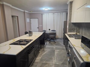 Una cocina moderna con una isla central, horno empotrado y lavadora.