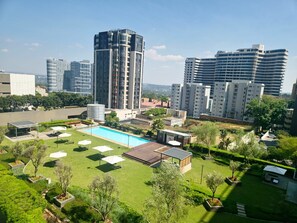 Un barrio residencial con piscina, céspedes verdes y edificios modernos al fondo.