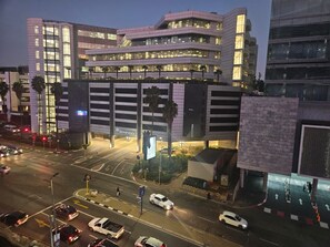 A multi-story building with a prominent 'Investec' sign, surrounded by a busy urban street at night. - Sandton Westpoint Luxury Apartments 172 (Sandton)