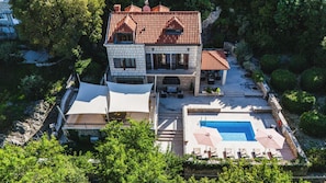 A large two-story house with a swimming pool, outdoor seating, and a garden.