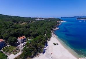 A coastal area with a beach, a small building with a red roof, and a clear blue sea. - Villa Franica (Dubrovnik)