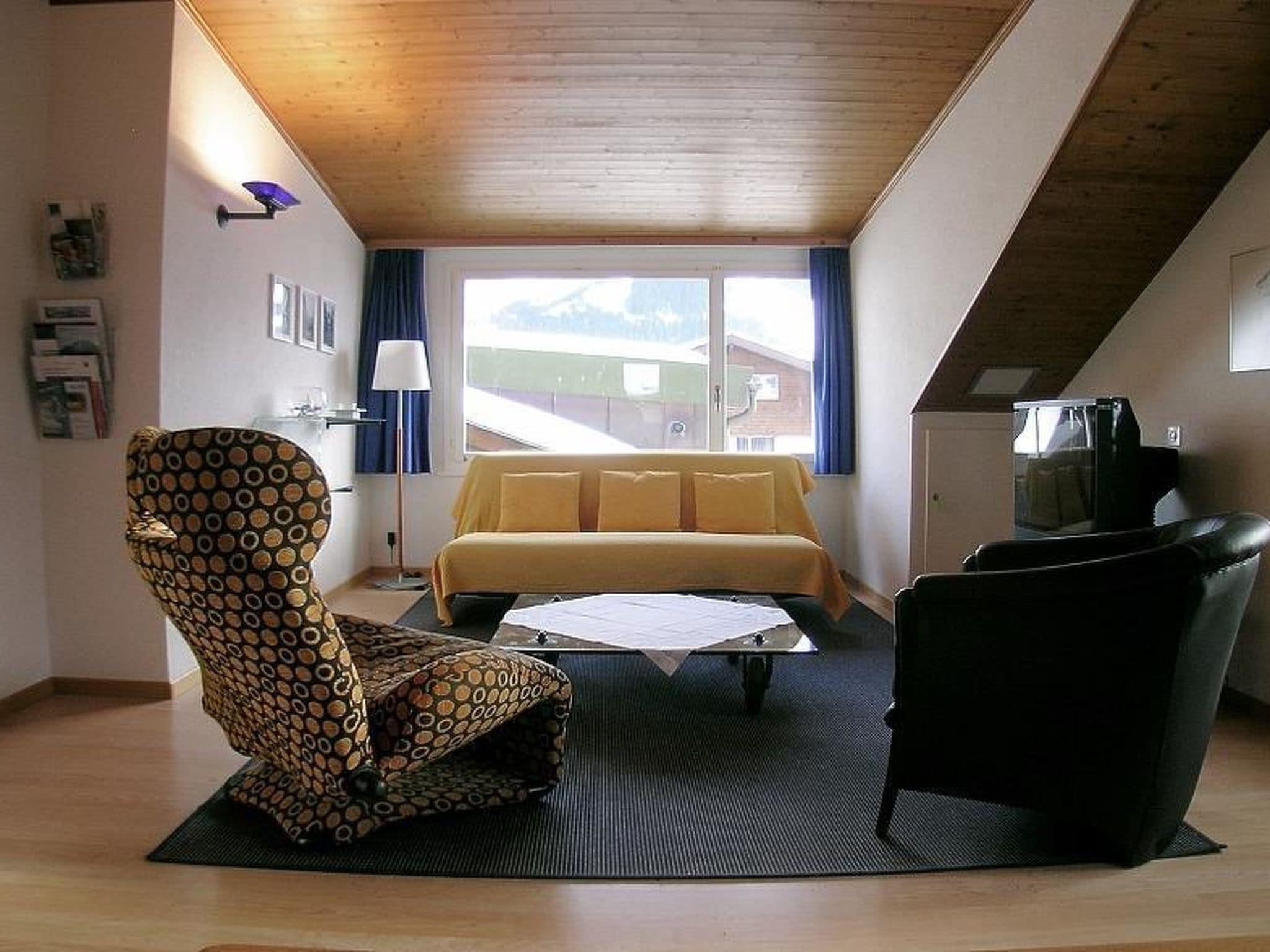 A room with a bed, a chair, a sofa, a coffee table, and a television.