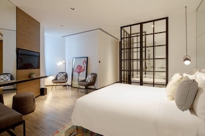 Een moderne hotelkamer met een groot bed, een bureau met stoel, een bank en een groot raam met uitzicht.
