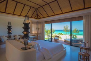 A hotel room with a large bed, a desk, and a view of the beach. - The Royal Sands Koh Rong (Sihanoukville)