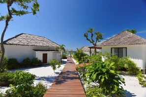 A pathway leading to beach huts with thatched roofs, surrounded by greenery and white sand. - The Royal Sands Koh Rong (Sihanoukville)