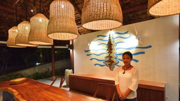 A reception area with a wooden reception desk, wicker pendant lights, and a wall with a blue wavy pattern.