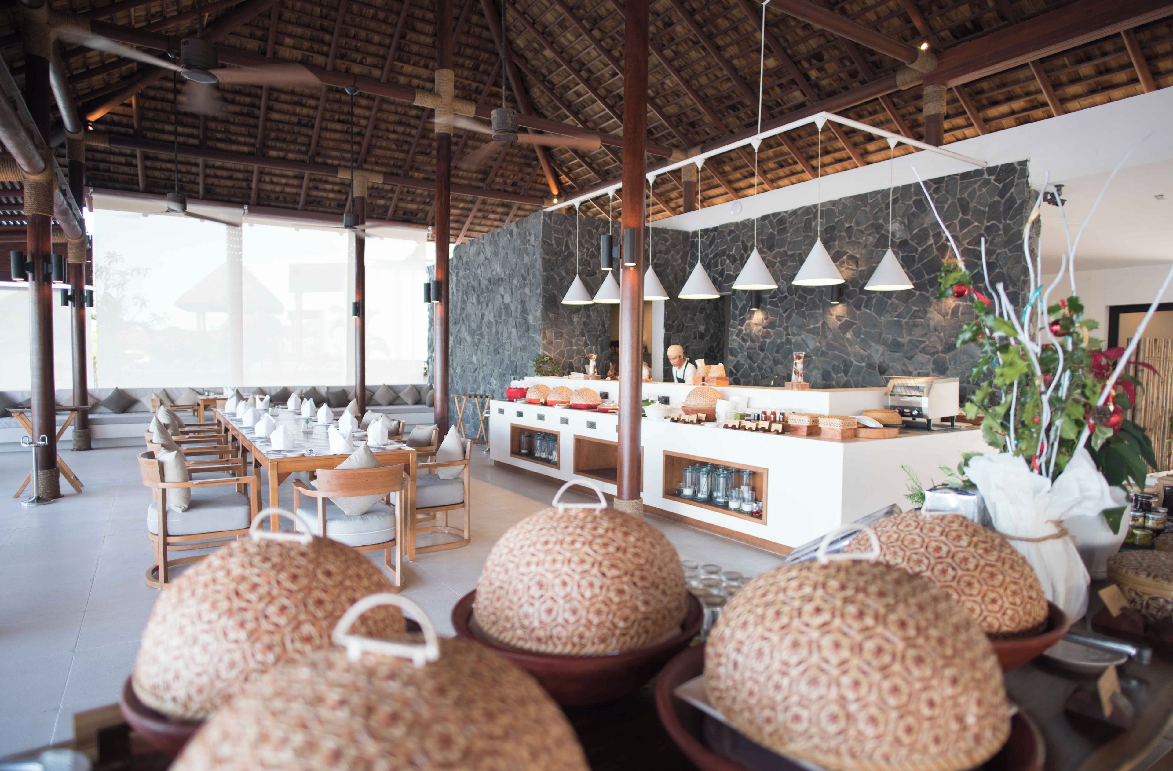 A restaurant with a high ceiling, stone wall, and a buffet area.