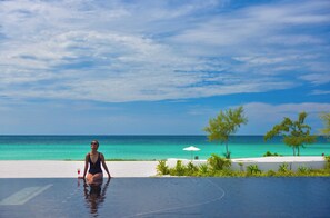 A person in a swimsuit by a pool with a view of the ocean and a clear sky. - The Royal Sands Koh Rong (Sihanoukville)