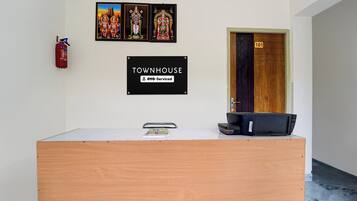 A reception desk with a sign indicating it is serviced by OYO, a wooden door with the number 101, and a fire extinguisher mounted on the wall.