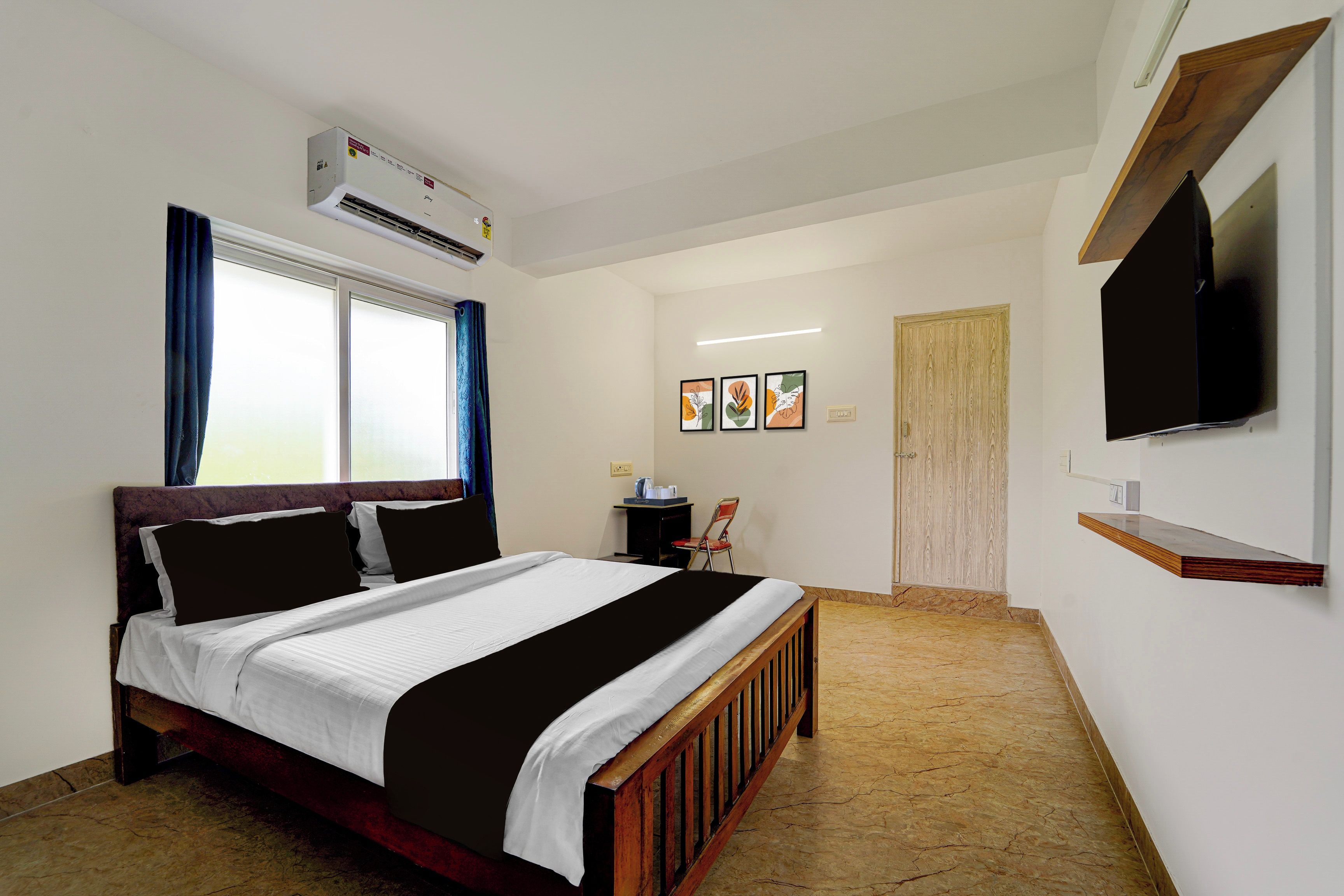 Un dormitorio con cama, aire acondicionado, televisor, escritorio con silla y obra de arte en la pared.