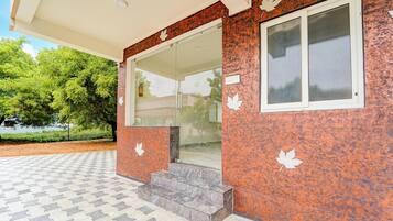 A building entrance with a glass door, a set of steps, and a window with a leaf decal.