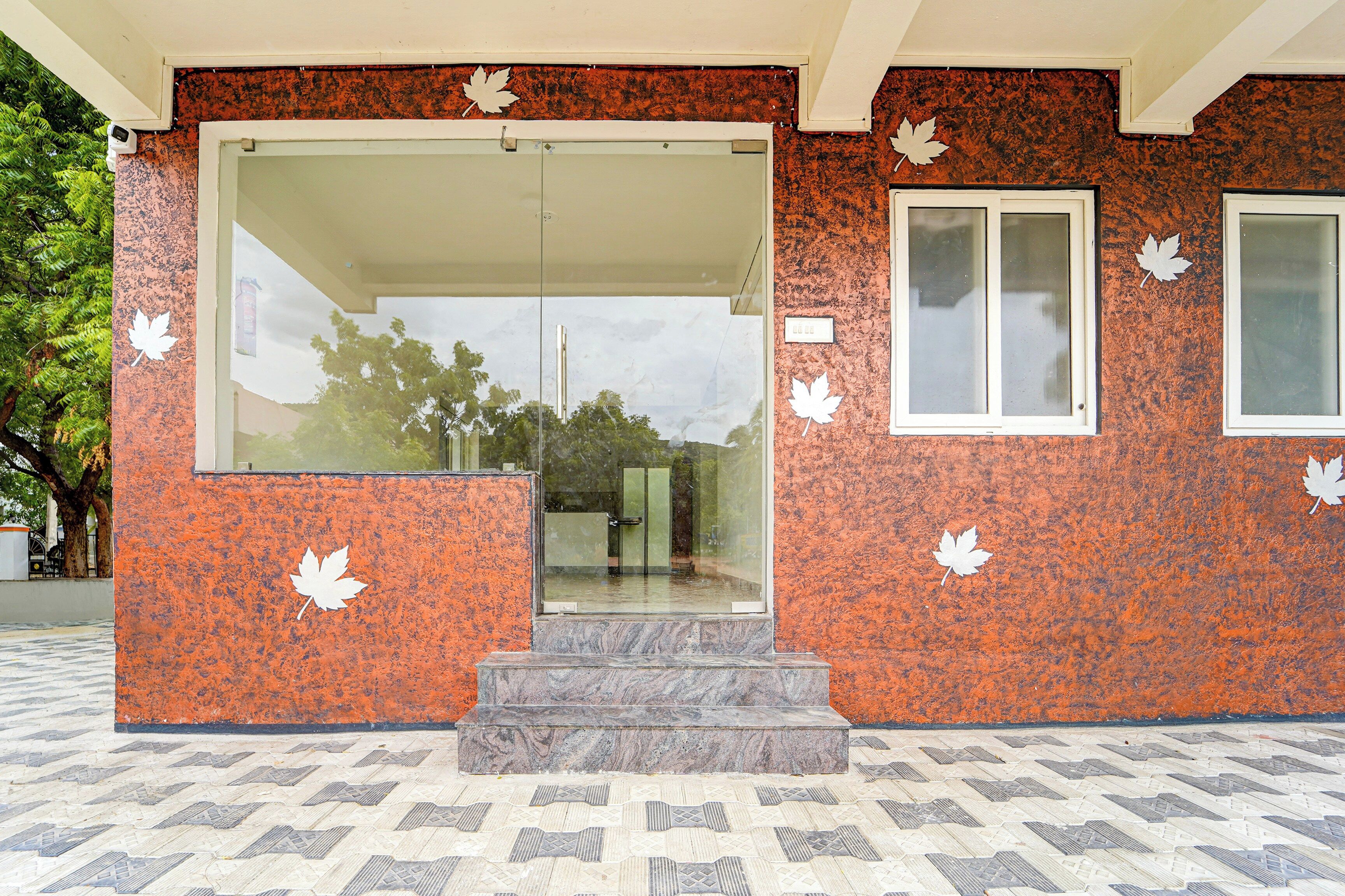 A building entrance with a glass door, a small window, and a set of steps leading up to the door.