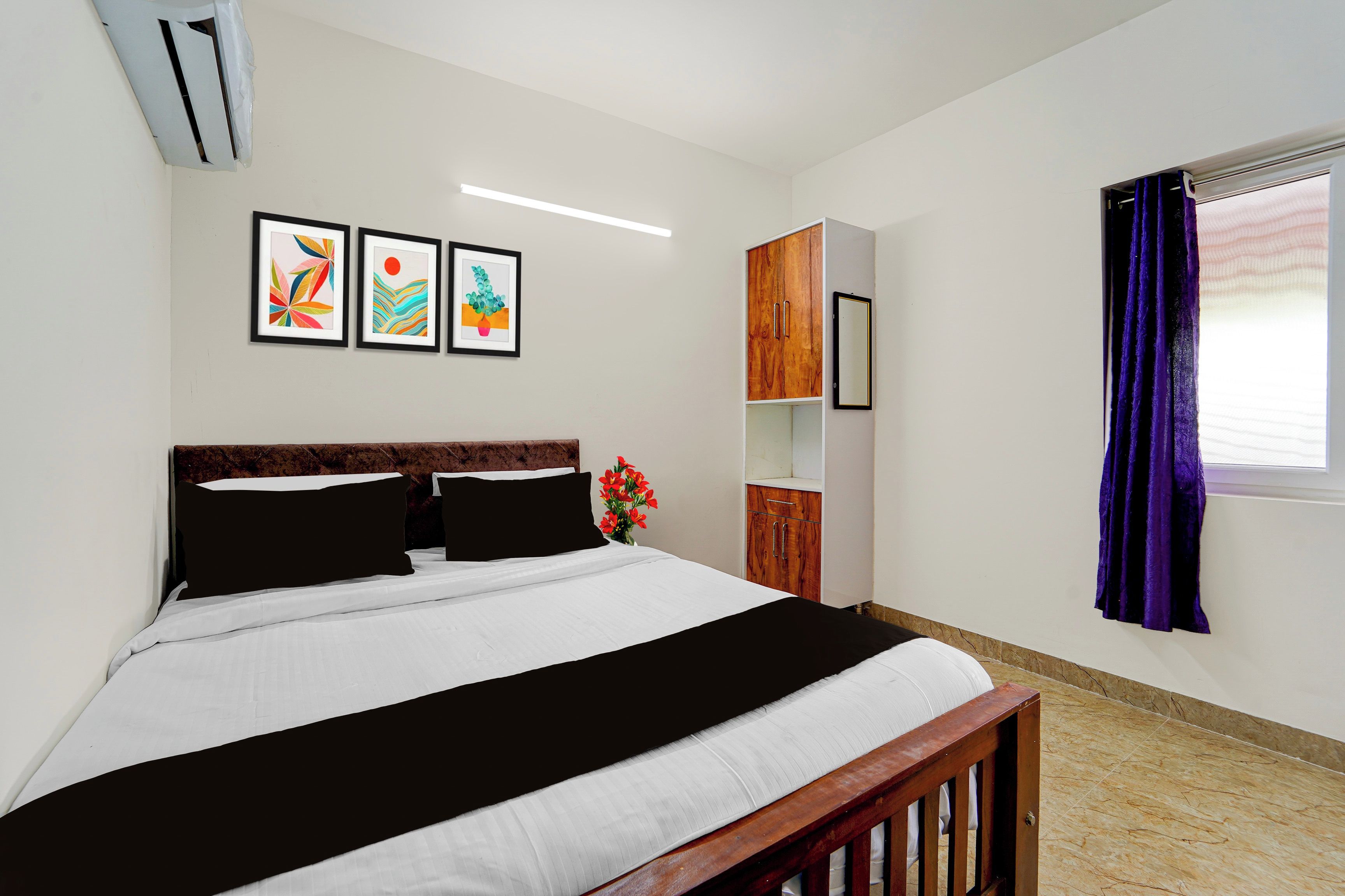 Un dormitorio con cama, armario, espejo y obras de arte en la pared.