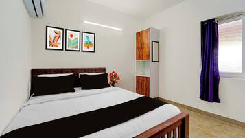 Un dormitorio con cama, armario, espejo y obras de arte en la pared.