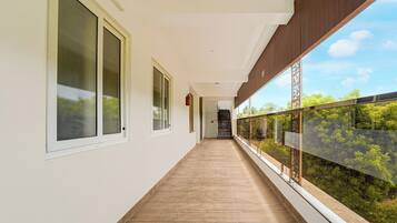 A corridor with large windows, a wooden floor, and a view of greenery outside.