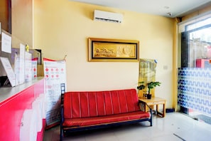 A reception area with a red sofa, a framed artwork, and informational posters on the wall. - Collection O Banda Aceh Near Masjid R Baiturrahman (Banda Aceh)