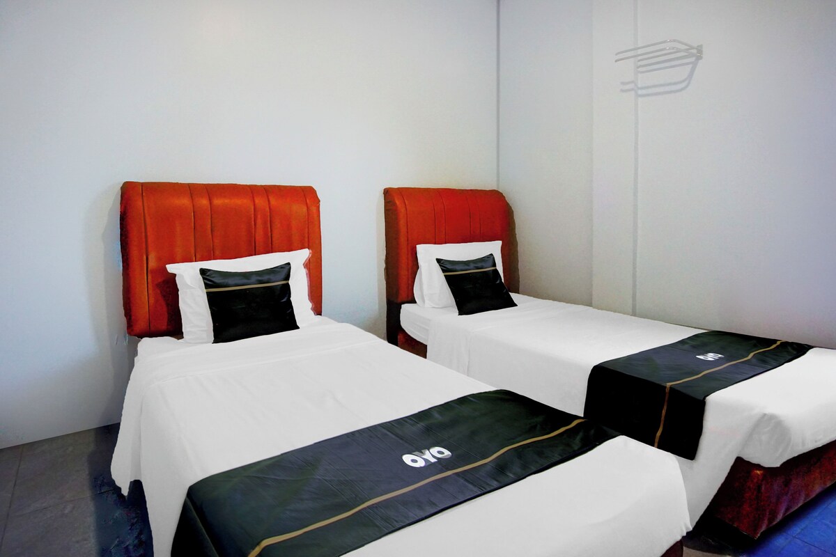 Una habitación de hotel con dos camas individuales, cada una con cabecero rojo y ropa de cama blanco y negro.