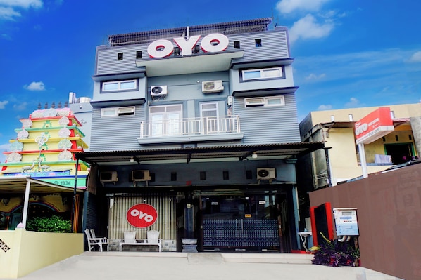 A building with a prominent 'OYO' sign, a traditional tiered structure with colorful decorations, and a modern facade with air conditioning units. - Collection O Banda Aceh Near Masjid R Baiturrahman (Banda Aceh)