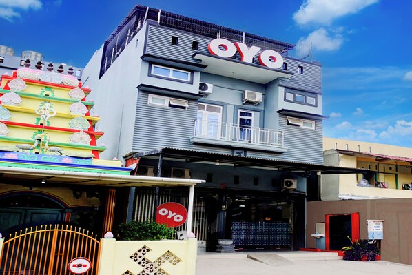 Un edificio con un llamativo letrero 'OYO', una entrada con portones y una estructura decorativa de colores a la izquierda.