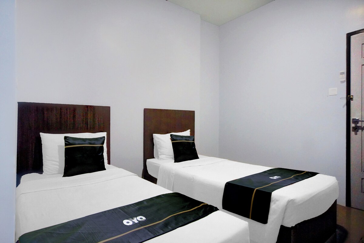 Dos camas individuales con cabeceras, ropa de cama blanca y un corredor de cama verde y negro.