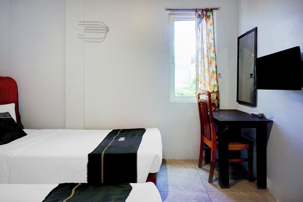 A hotel room with two beds, a desk, a chair, a window with curtains, and a television mounted on the wall. - Collection O Banda Aceh Near Masjid R Baiturrahman (Banda Aceh)