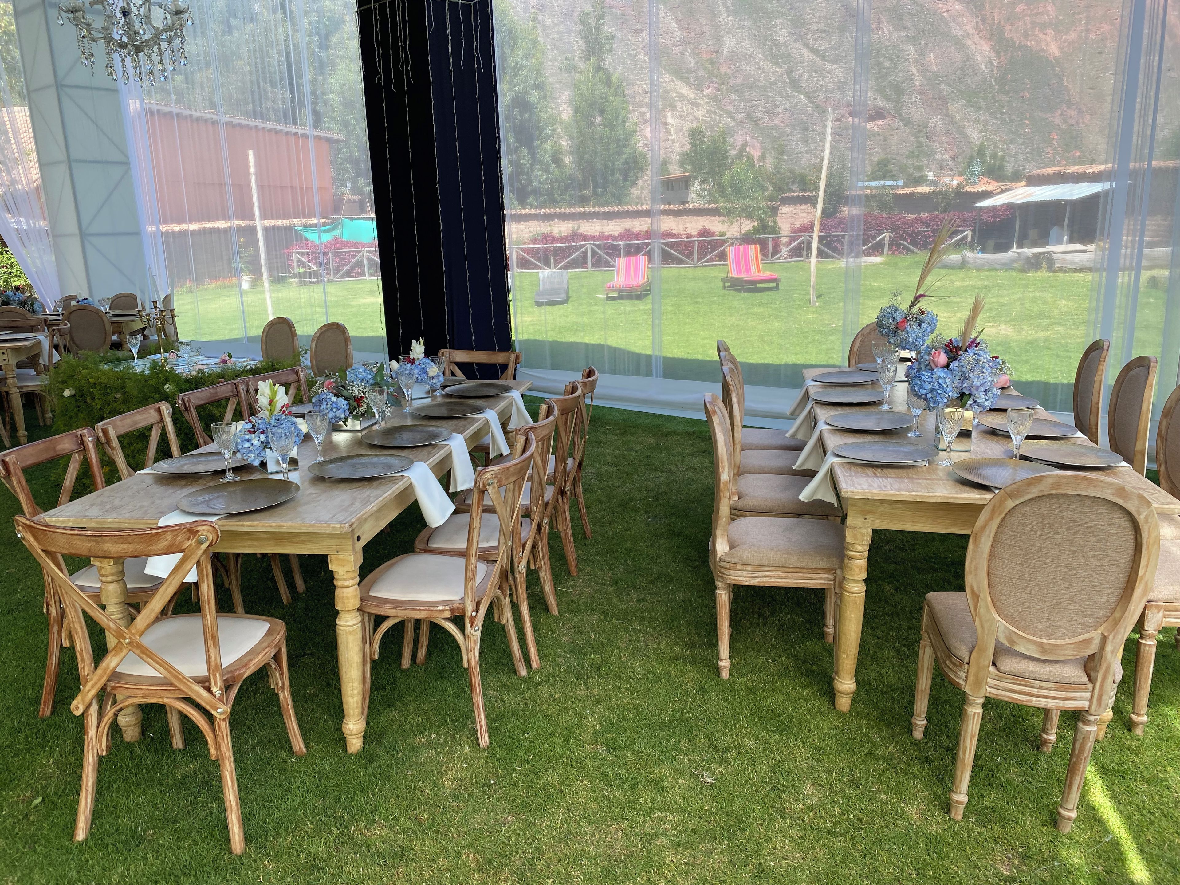 Un espace de restauration en plein air, aménagé avec des tables et des chaises en bois, de la vaisselle et des centres de table floraux.