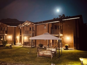 Un edificio con área de estar techada al aire libre, un balcón y una entrada bien iluminada.