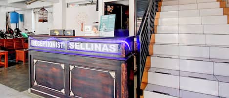 Un mostrador de recepción con un cartel que dice 'RECEPTIONIST SELINAS' y una escalera a la derecha.