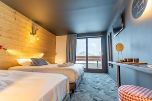 A hotel room with two beds, a large window, a mirror, and a small table with cups.