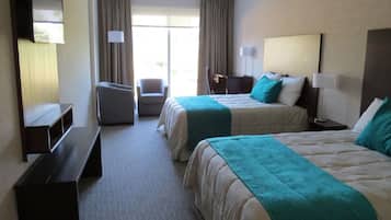 Habitación de hotel con dos camas, un escritorio, una silla y un televisor.