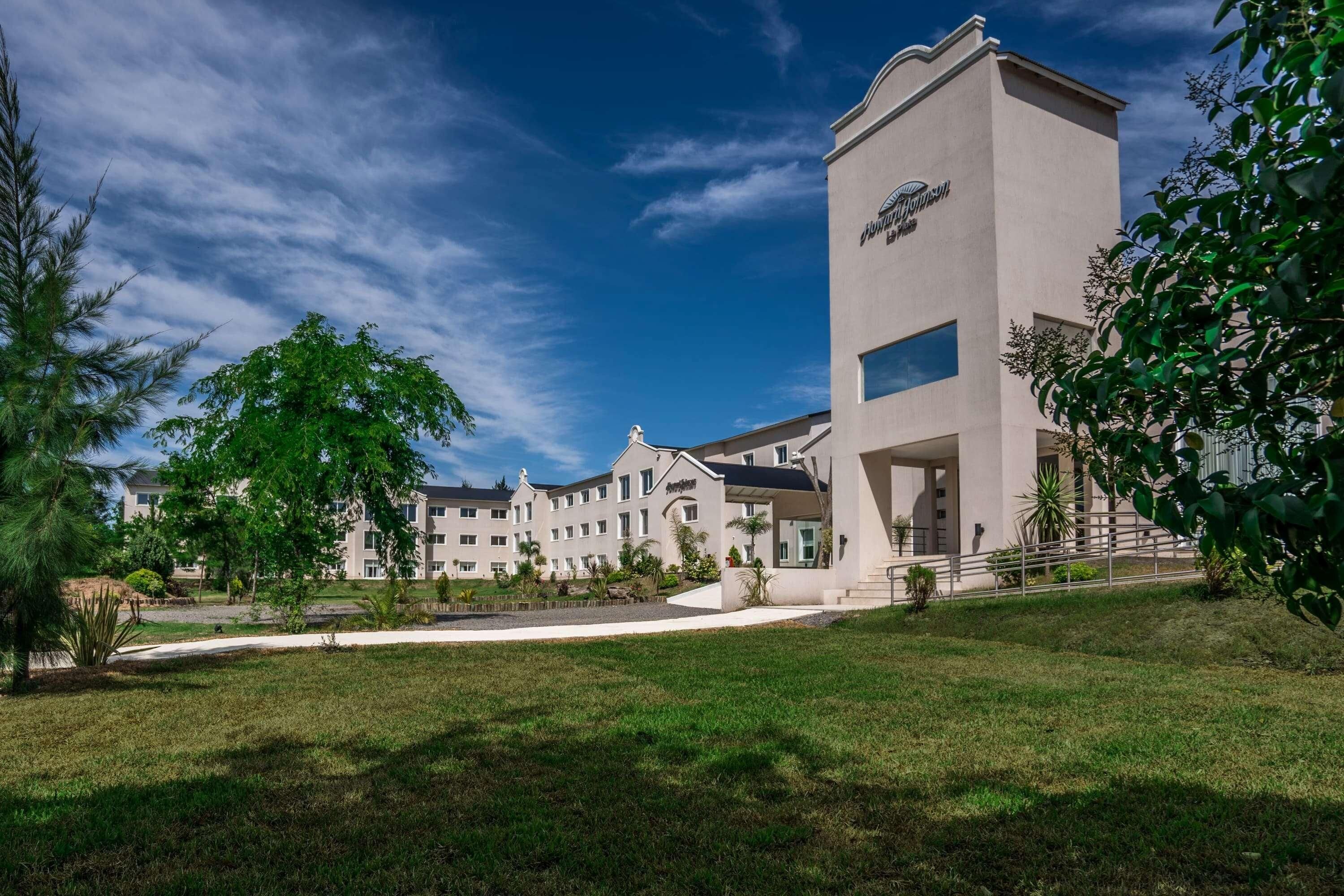 A multi-story hotel with a central tower, a covered entrance, and a well-maintained lawn.