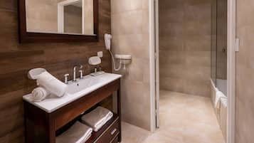Un baño moderno con tocador de madera, un espejo grande, ducha y azulejos color beige.