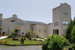Un hôtel Howard Johnson doté d’une entrée centrale, d’une horloge et d’un jardin agrémenté de diverses plantes.