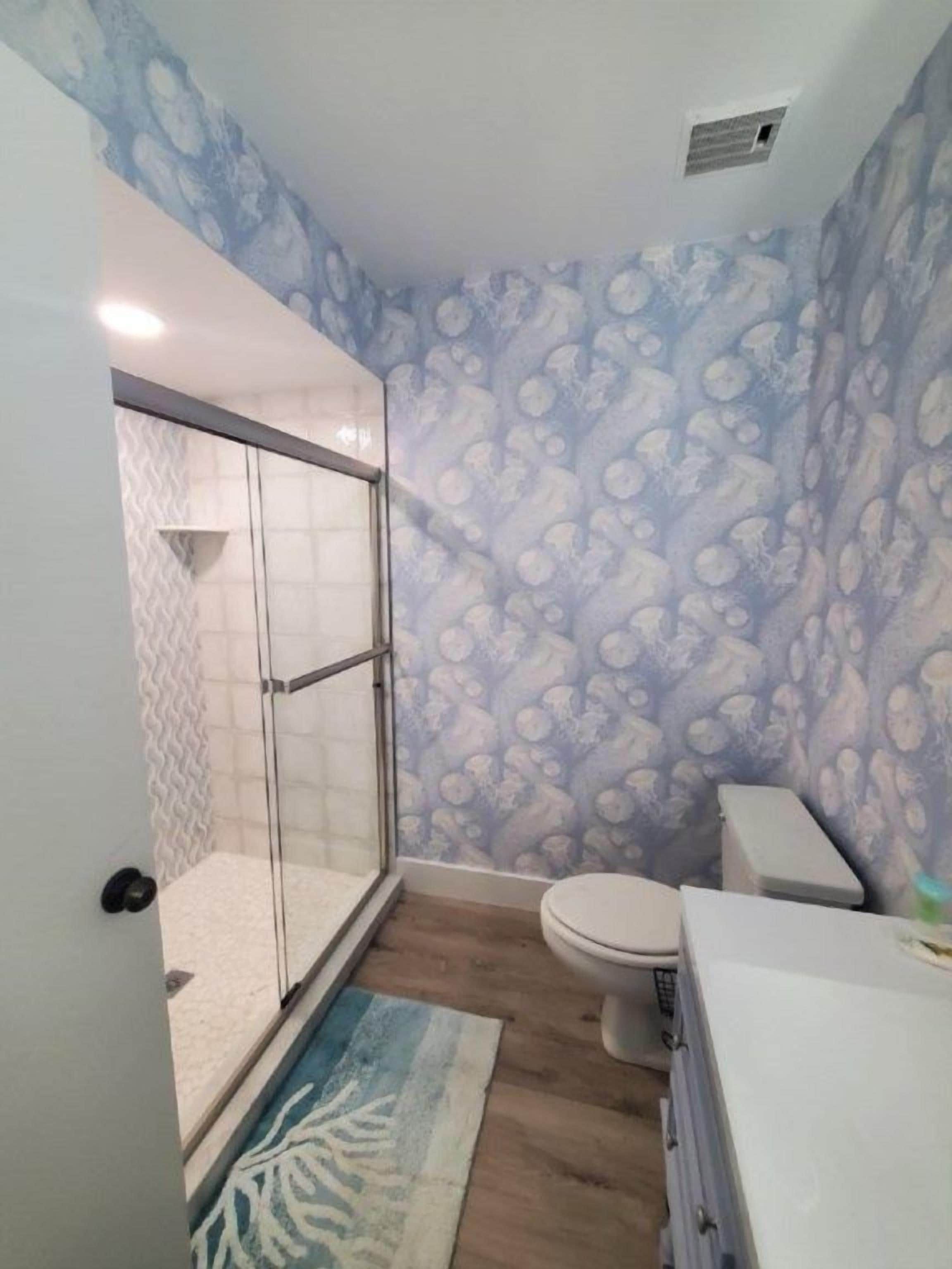 Une salle de bain avec douche, toilettes et lavabo.