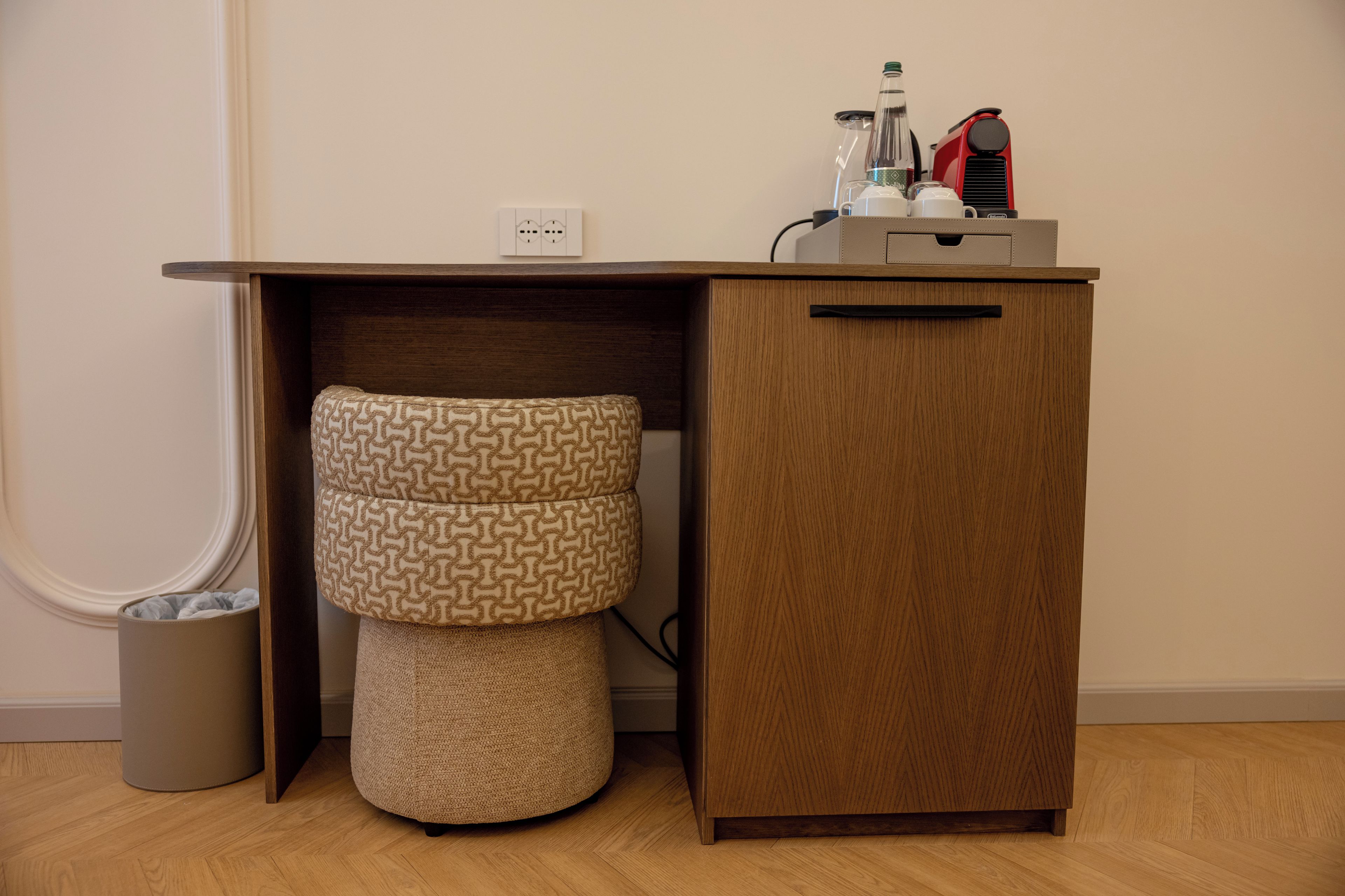A wooden desk with a woven stool underneath.