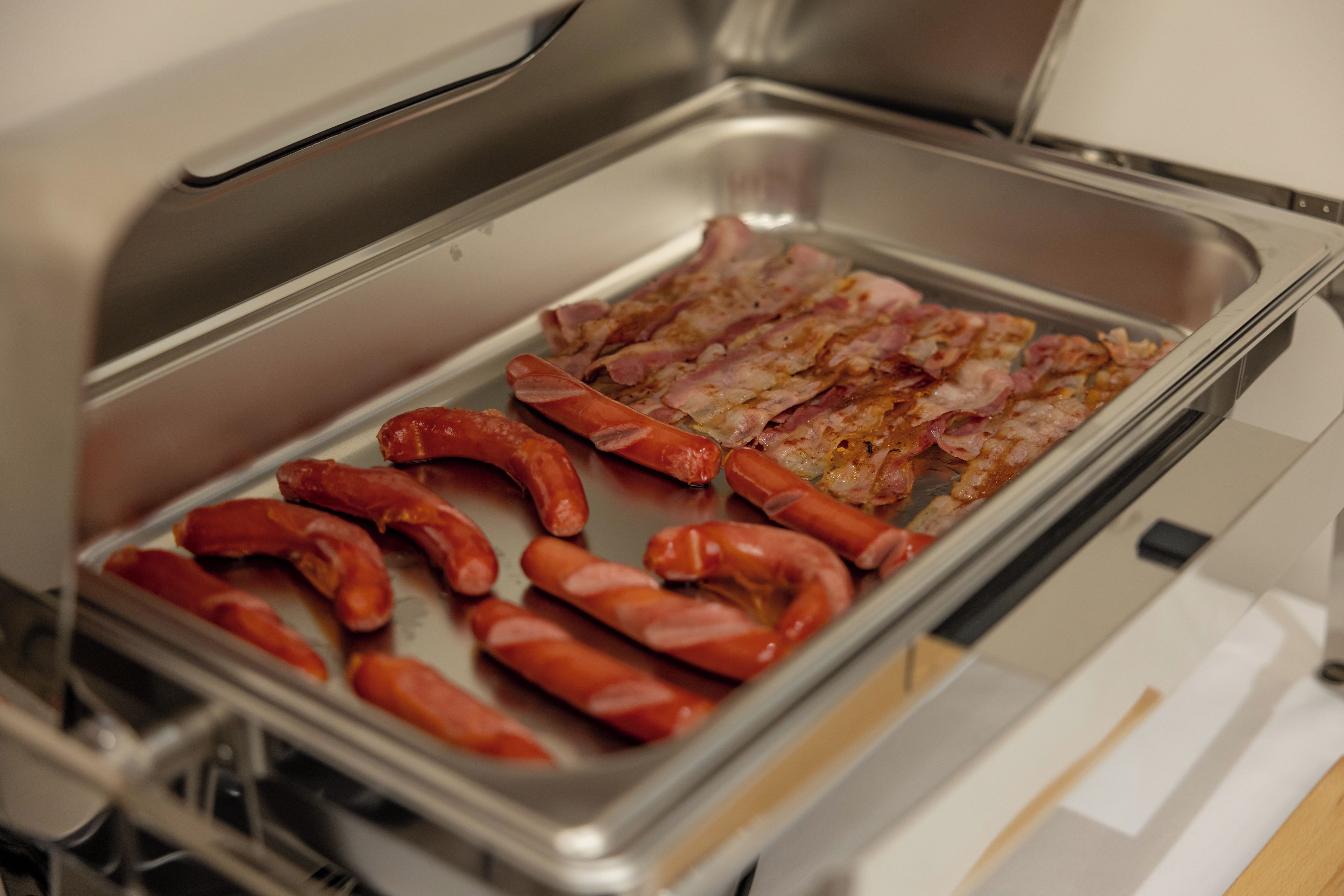 Un buffet con diverse carni, tra cui salsicce e pancetta.